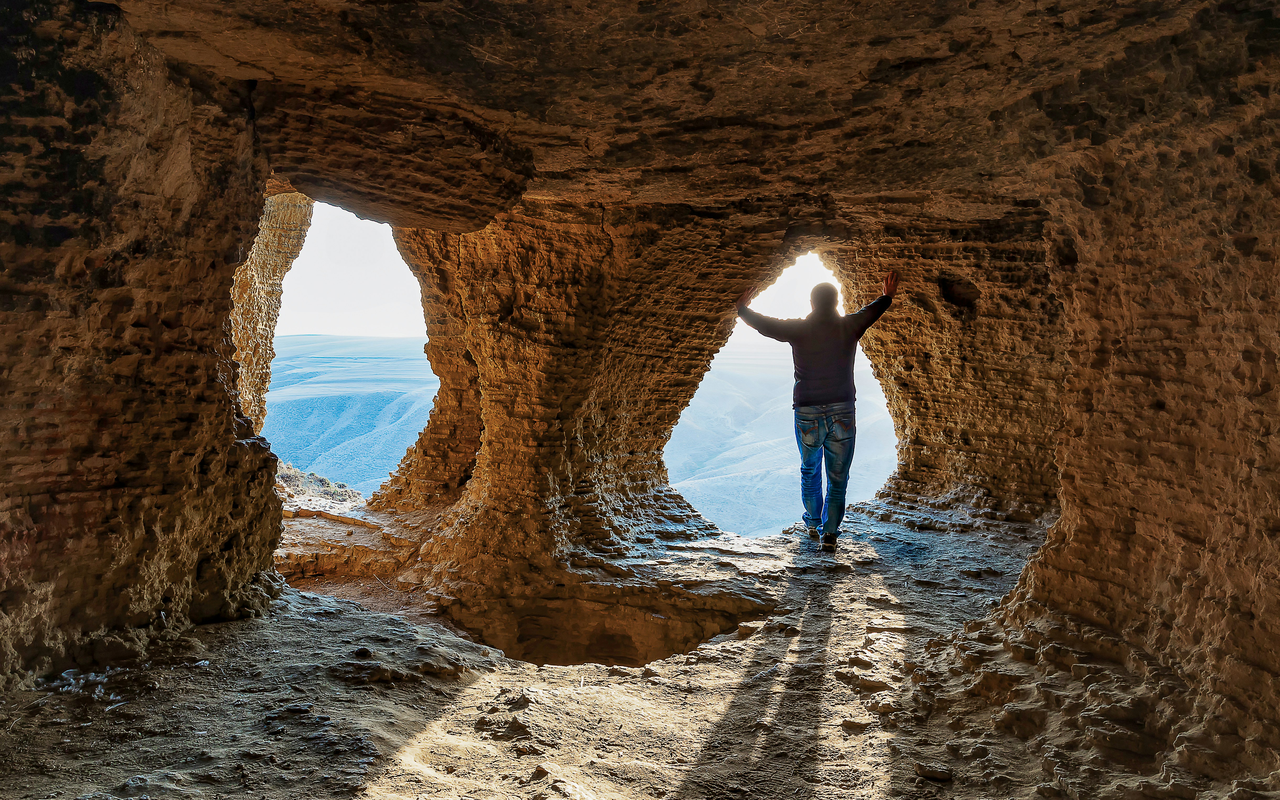 Man standing inside a cave with a view of the landscape in Matera.