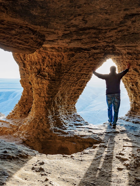 Man standing inside a cave with a view of the landscape in Matera.