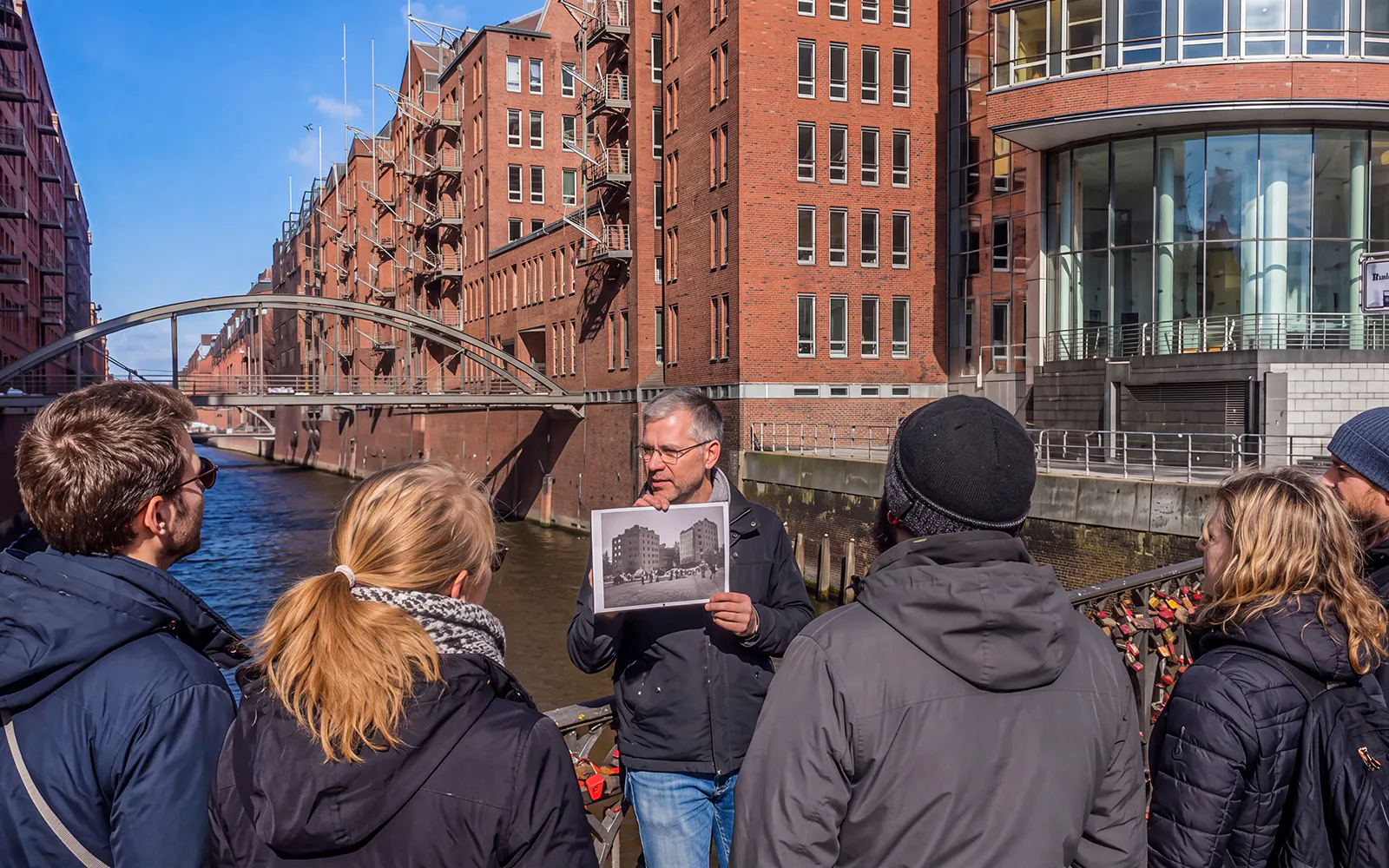 Guided tour group at Speicherstadt, Hamburg, with guide holding historical photo.