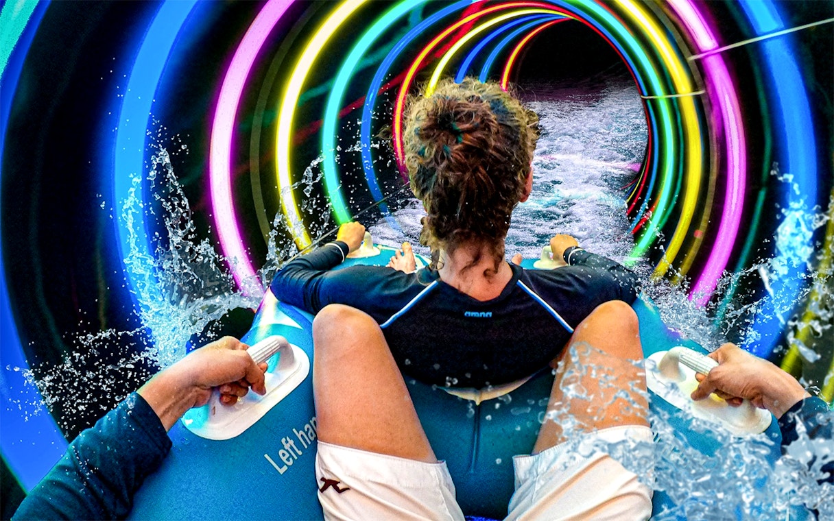 Person riding a water slide with colorful lights at SplashMania Waterpark, Gamuda Cove, Selangor.