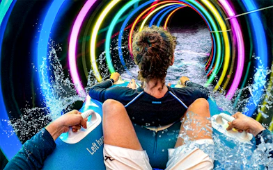 Person riding a water slide with colorful lights at SplashMania Waterpark, Gamuda Cove, Selangor.