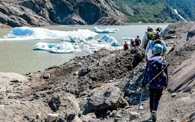 Hikers trekking along rocky terrain near Mendenhall Glacier, Alaska.