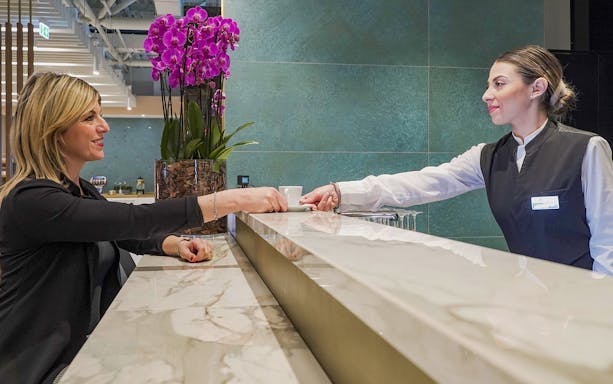Customer receiving a drink at Rome Fiumicino Airport premium lounge counter.