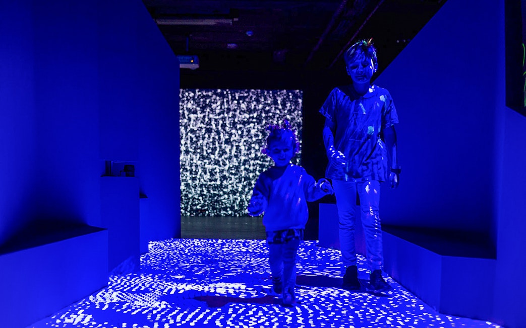 Children exploring light patterns at Lumia Gallery's Audiovisual Light Art Exhibition.