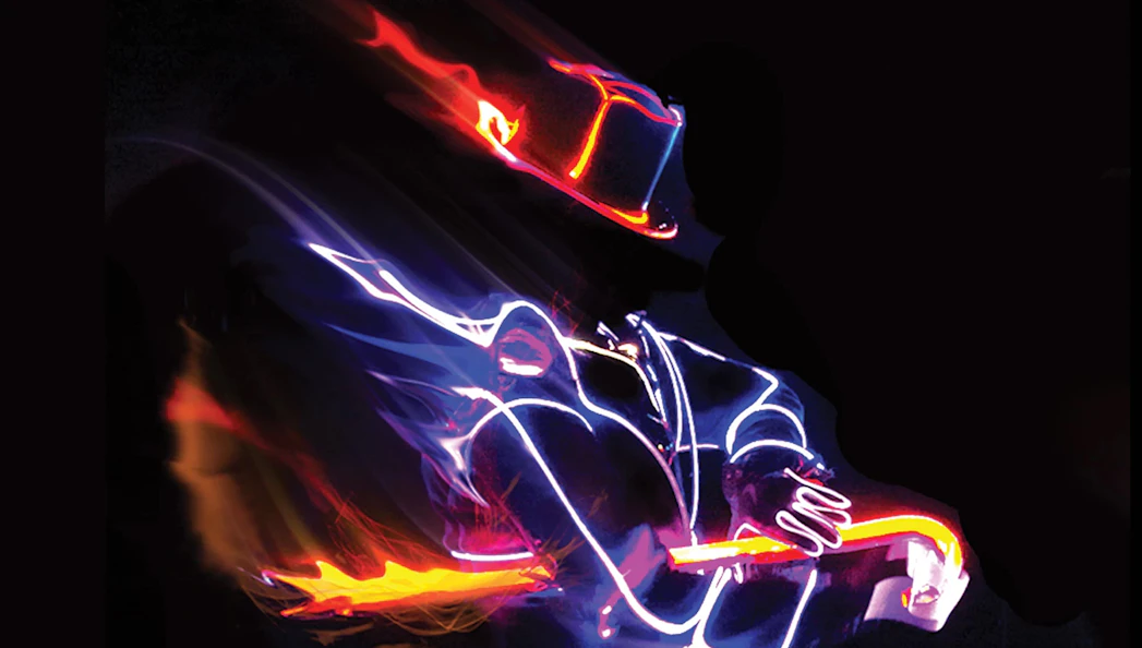 Performer in illuminated costume playing guitar at iLuminate show.