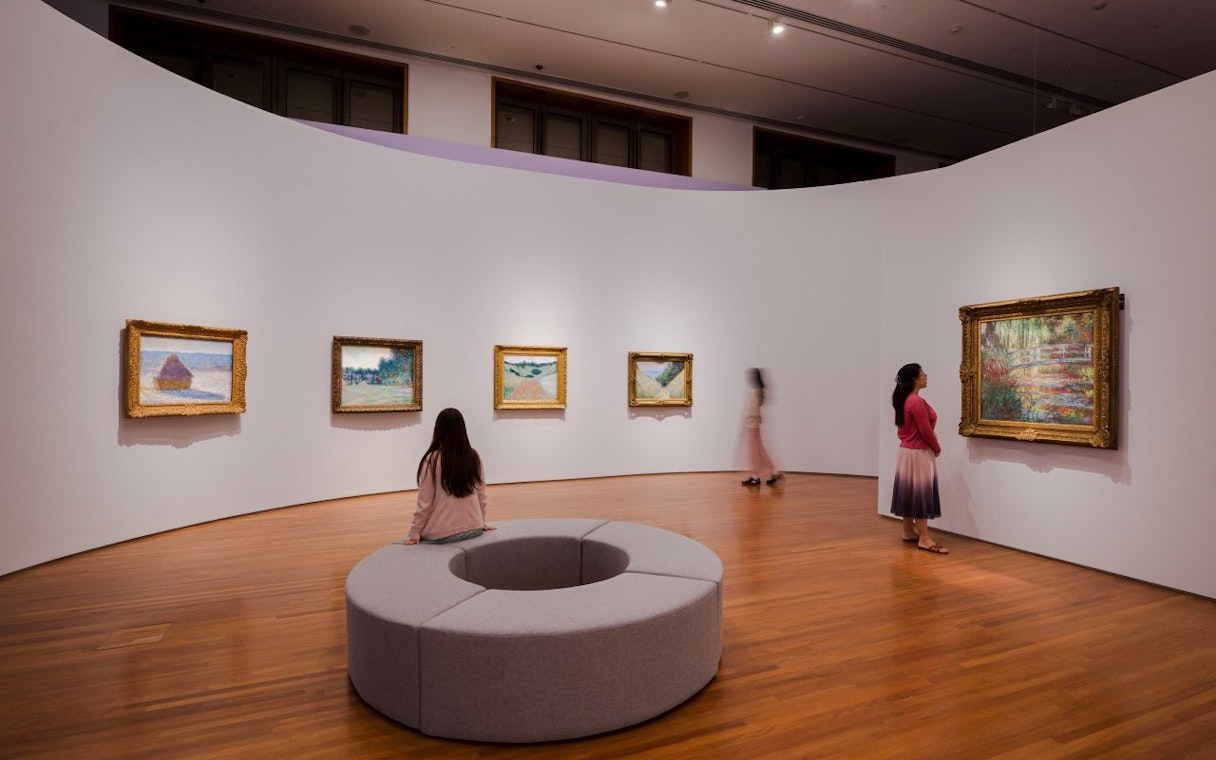 Tourists viewing impressionist paintings at National Gallery Singapore.