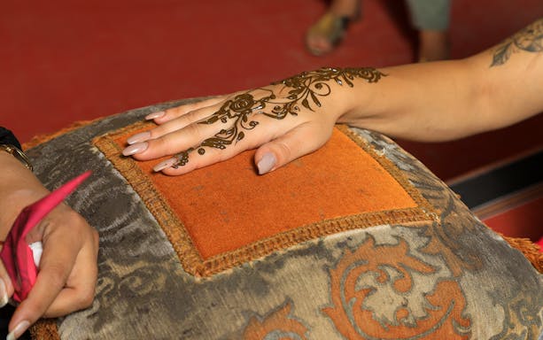 Henna design being applied on a hand during Arabian Dunes Premium Safari.