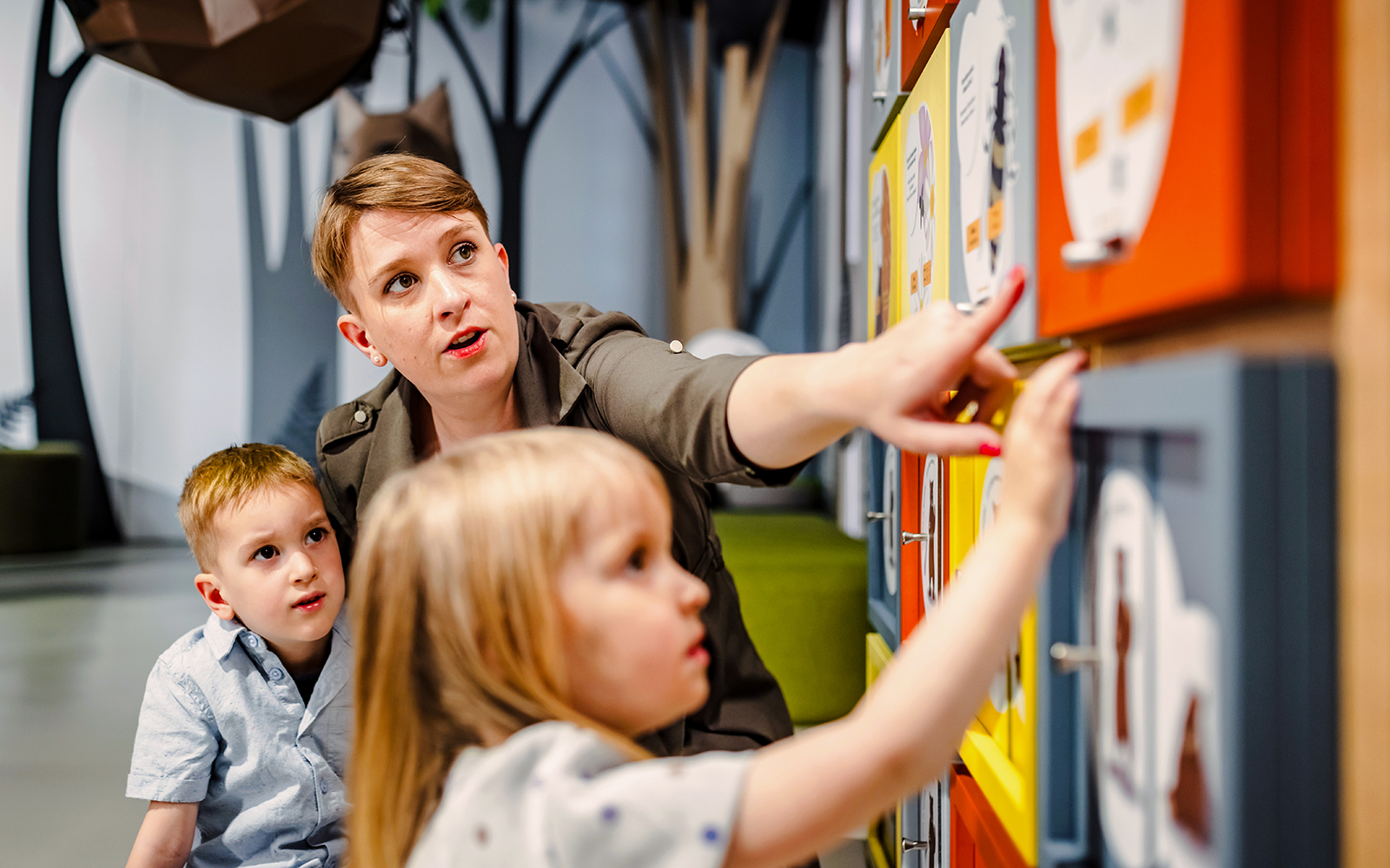 Mother and two children exploring interactive exhibit at natural history museum.