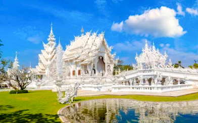 White Temple in Chiang Rai with intricate architecture and reflection in pond.