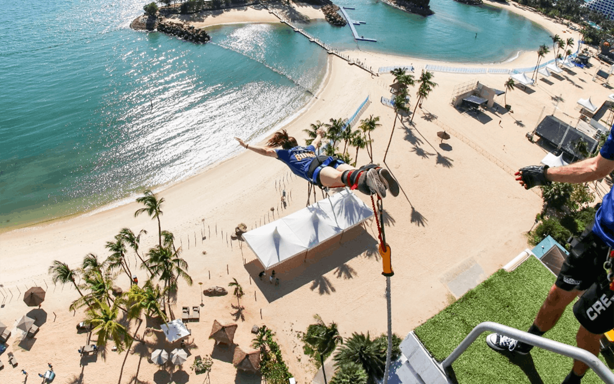 Person bungee jumping at Skypark Sentosa by AJ Hackett, overlooking the beach and ocean.
