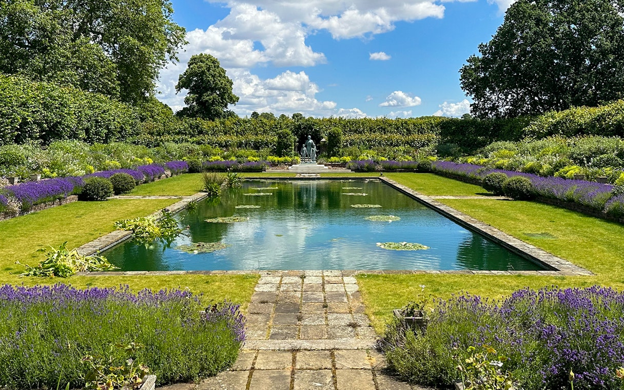 Kensington Palace gardens with pond, lavender borders, and statue in London.