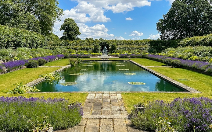 Kensington Palace gardens with pond, lavender borders, and statue in London.
