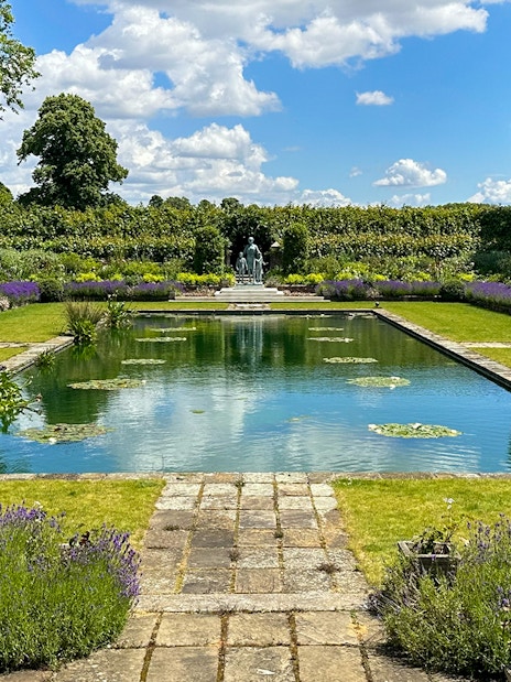 Kensington Palace gardens with pond, lavender borders, and statue in London.