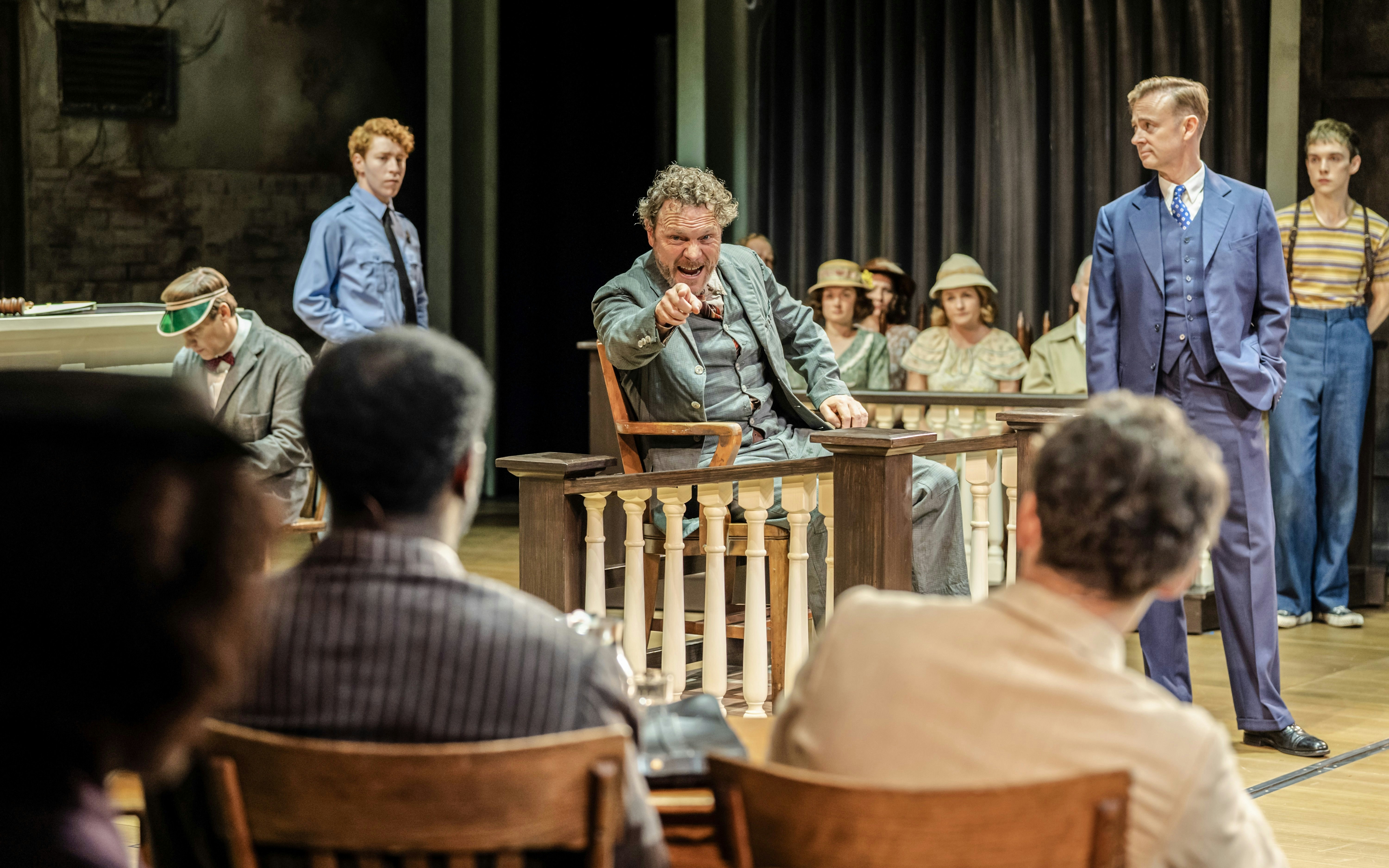 Courtroom scene from "To Kill a Mockingbird" West End show, actor pointing from witness stand.