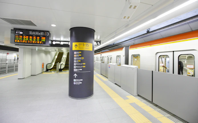 Train platform at Wako-shi Station, Tokyo, Japan, with escalator and train doors open.