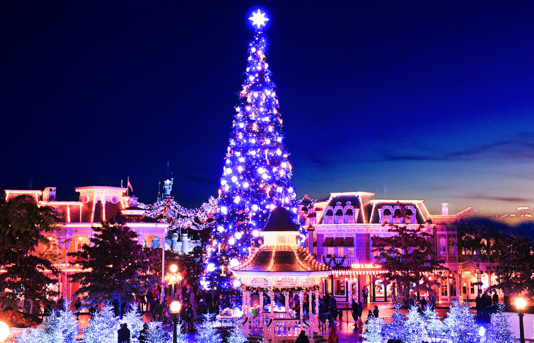 Festive Christmas tree illuminated at night in Disneyland Paris.