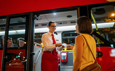 Tour guide handing ticket to tourist at bus entrance.
