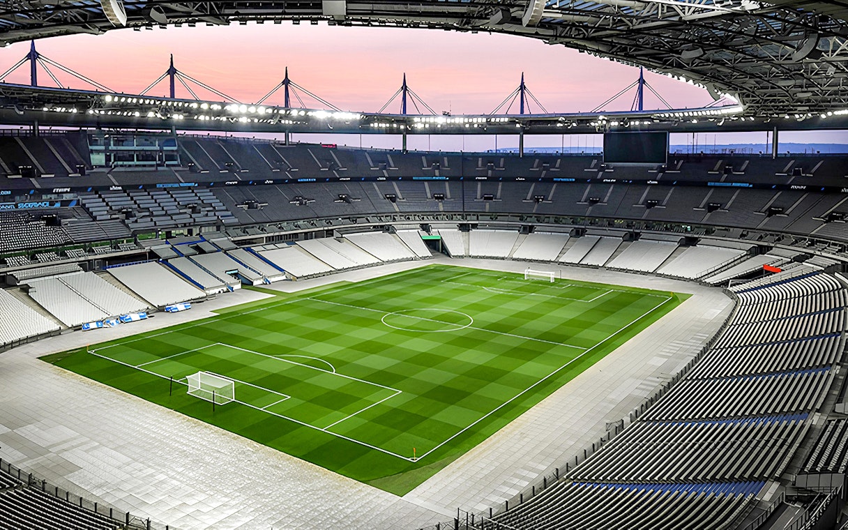 Aerial view of Stade de France stadium with empty seats and green field.