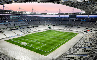 Aerial view of Stade de France stadium with empty seats and green field.