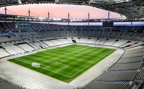 Aerial view of Stade de France stadium with empty seats and green field.