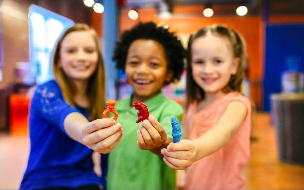 Children holding colorful crayon-shaped rings at Crayola Experience Orlando.