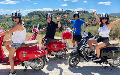 Group on Vespas enjoying Chianti countryside with San Gimignano skyline in background.