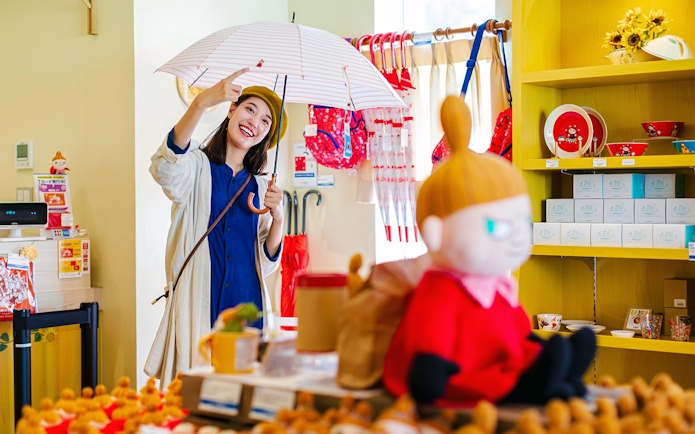 Visitor enjoying Moominvalley Park shop with Moomin merchandise and umbrellas.