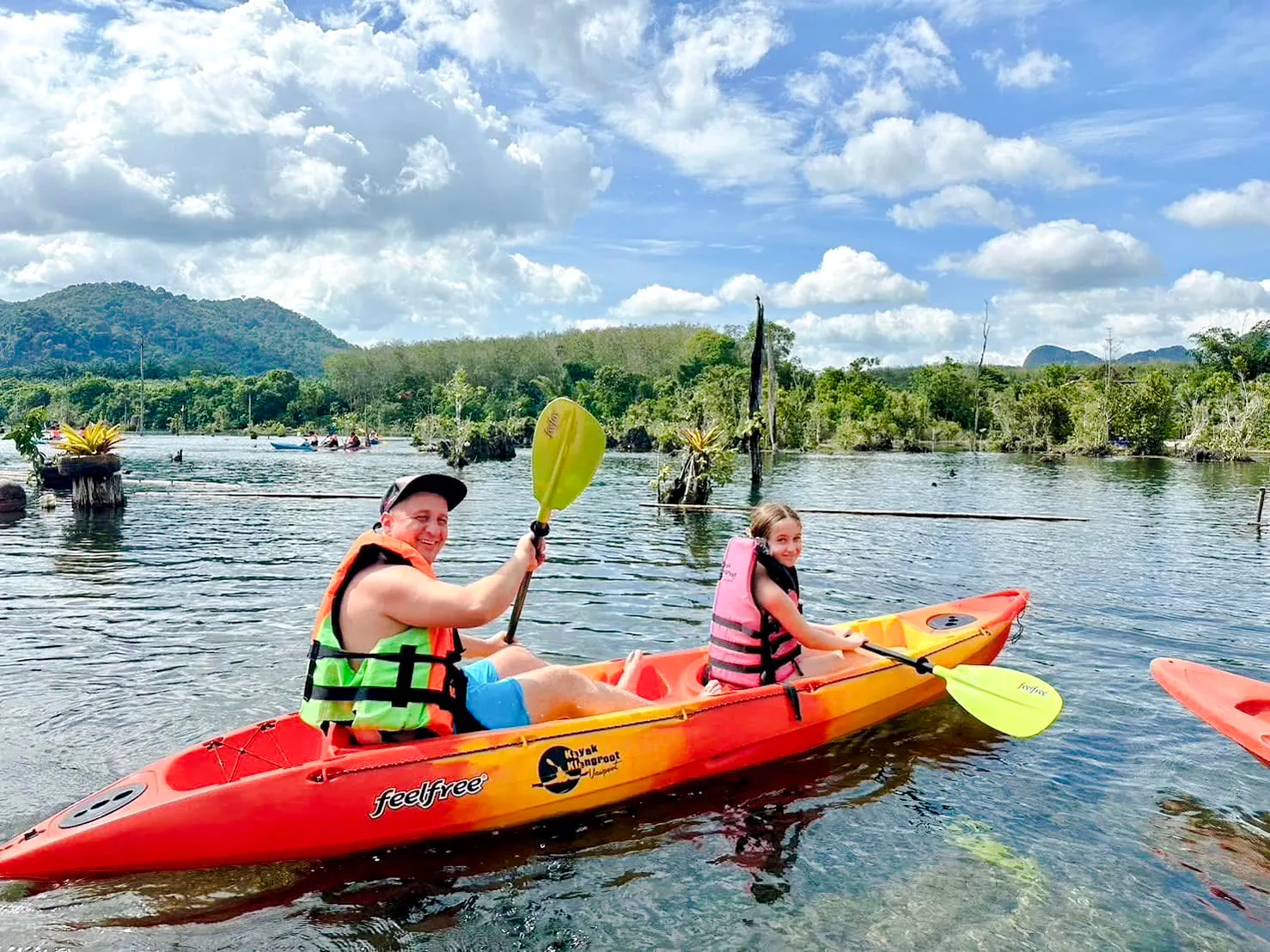 Kayaking on Khlong Rood in Krabi with lush greenery and mountains in the background.