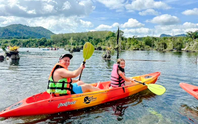 Kayaking on Khlong Rood in Krabi with lush greenery and mountains in the background.