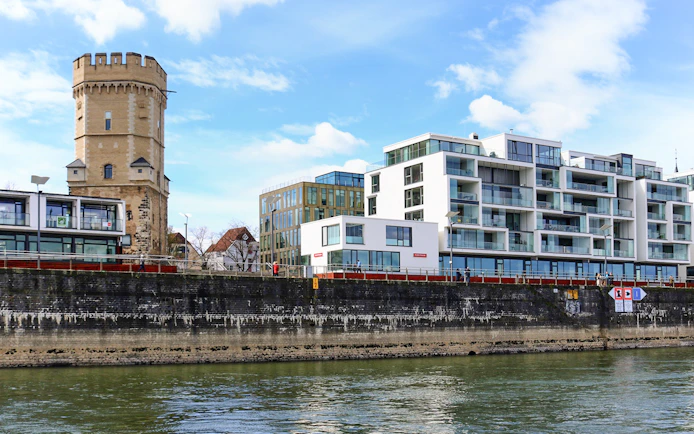 Cologne riverside with historic tower and modern buildings on skyline tour.