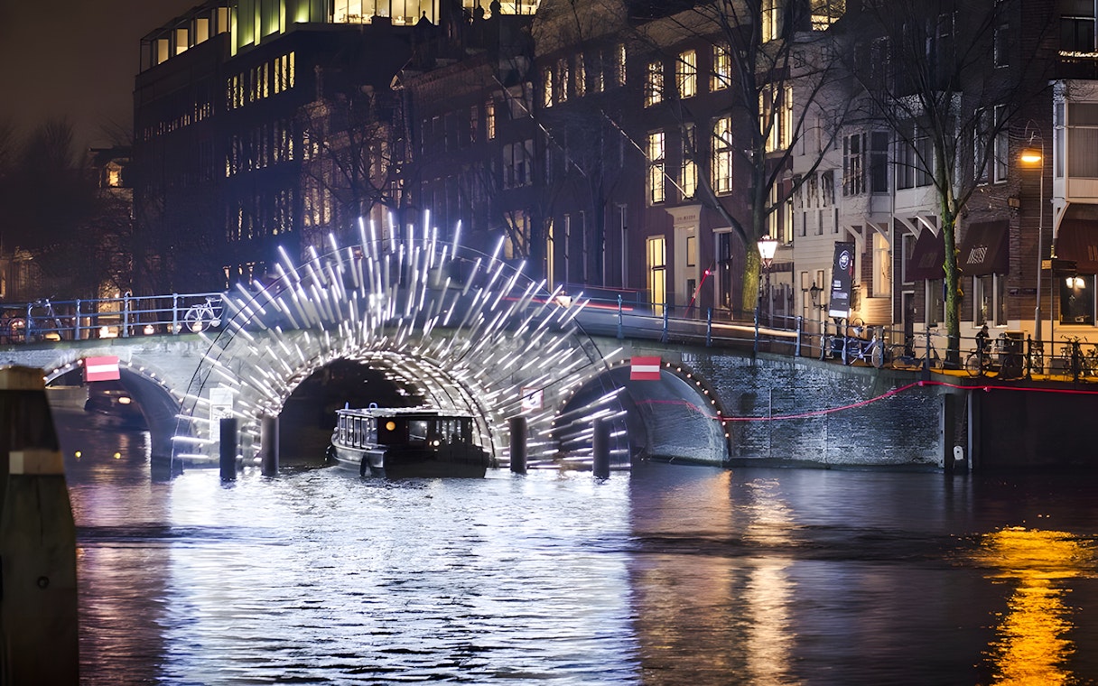 Cruise boat under illuminated arch at Amsterdam Light Festival.