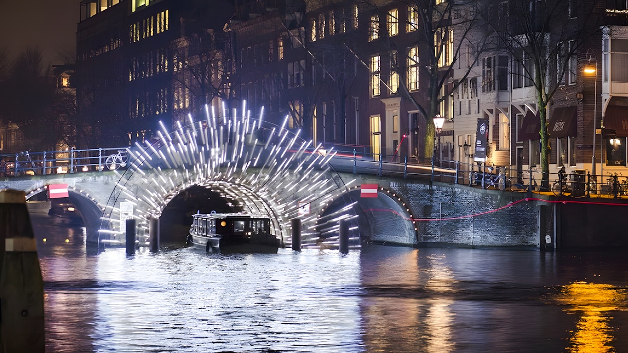 Cruise boat under illuminated arch at Amsterdam Light Festival.