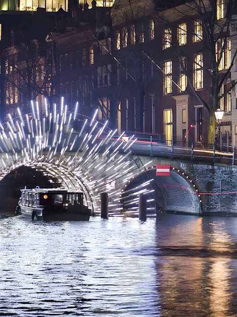 Cruise boat under illuminated arch at Amsterdam Light Festival.
