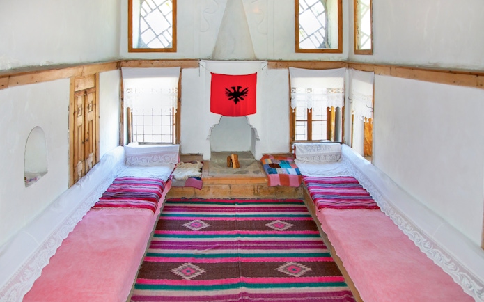 Traditional Albanian room with colorful rugs and benches inside ethnographic museum, Kruje, Albania.
