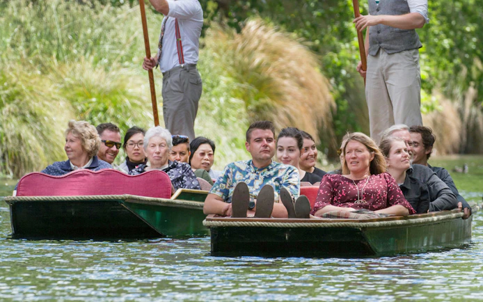 Punting tour on the Avon River in Christchurch with passengers enjoying the scenic ride.