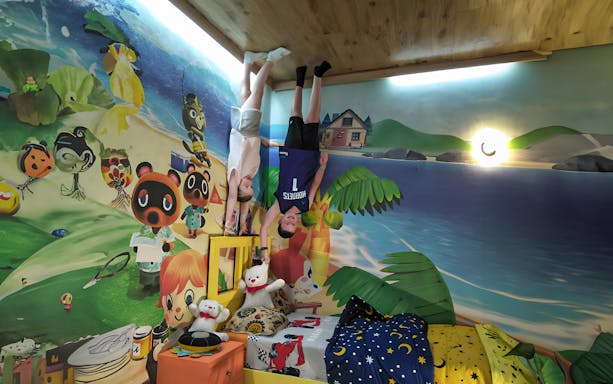 Visitors posing upside down in a colorful, cartoon-themed room at Upside Down World Bali.