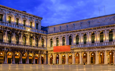 Venice's Museo Correr facade illuminated at dusk, part of the Venice Museums Pass.