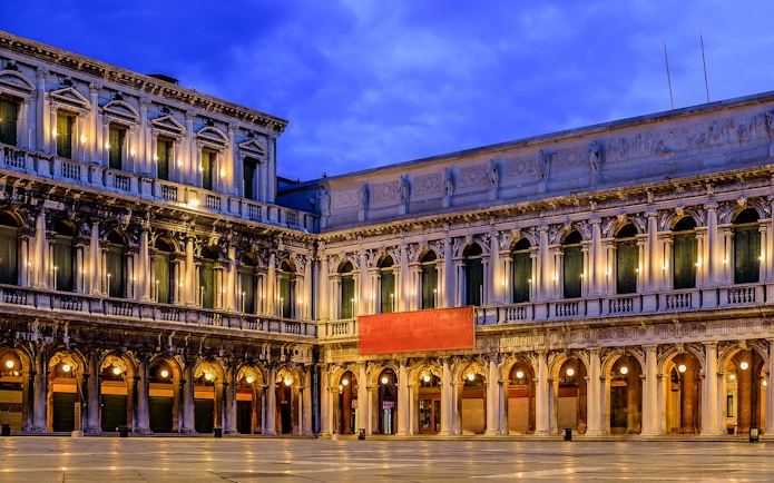 Venice's Museo Correr facade illuminated at dusk, part of the Venice Museums Pass.