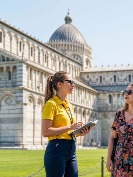Guide talking to a couple in front of Pisa Cathedral and Leaning Tower, Italy.