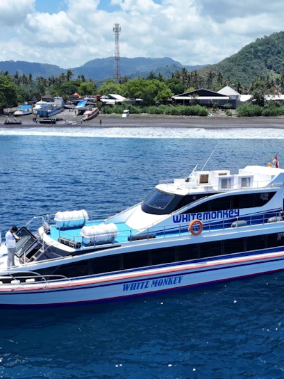 Boats docked at the pier near Nusa Penida with lush hills in the background.