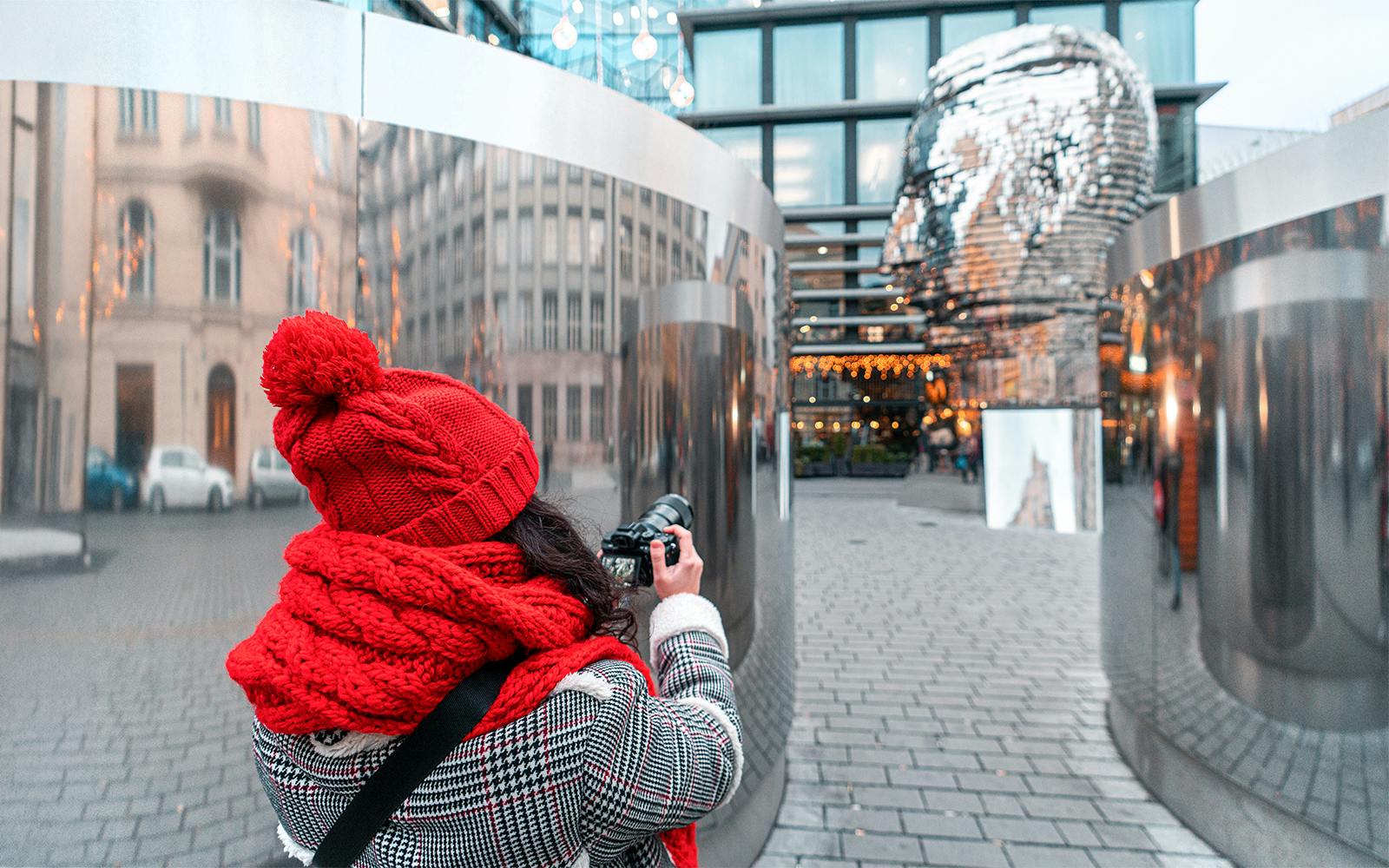 Tourist photographing Franz Kafka sculpture in Prague.
