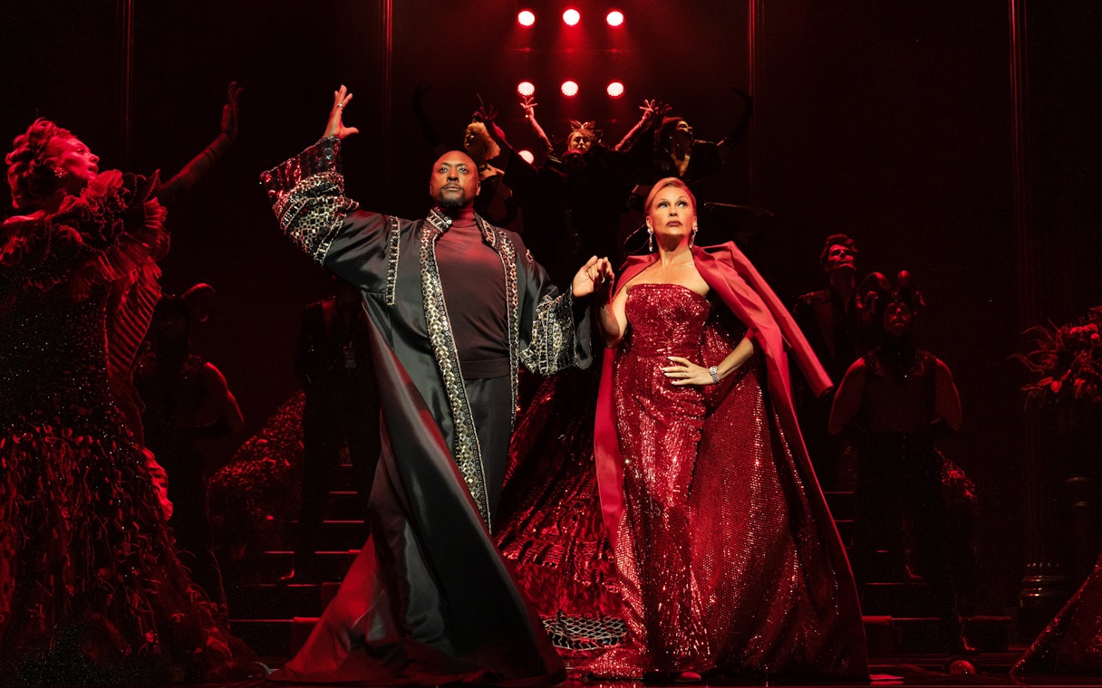 Stage performance of The Devil Wears Prada West End show with actors in elaborate costumes.