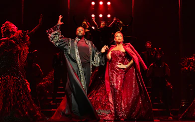 Stage performance of The Devil Wears Prada West End show with actors in elaborate costumes.