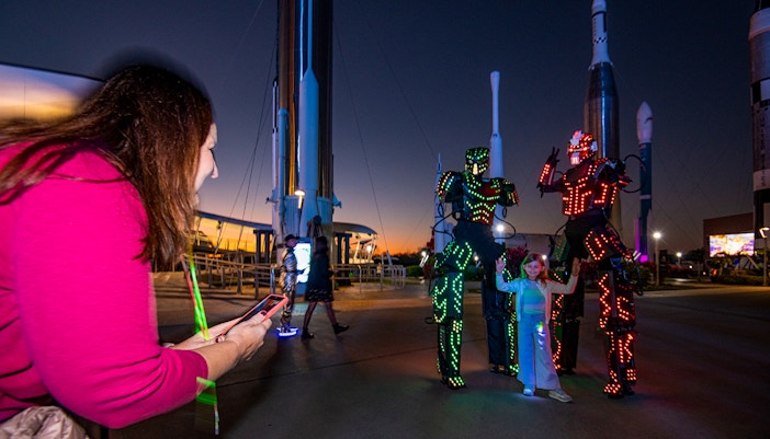 Visitors enjoying illuminated robot performers at Kennedy Space Center during Kennedy Under The Stars event.