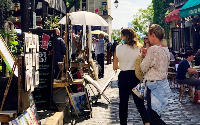 Tourists exploring Montmartre art market on a walking tour in Paris.