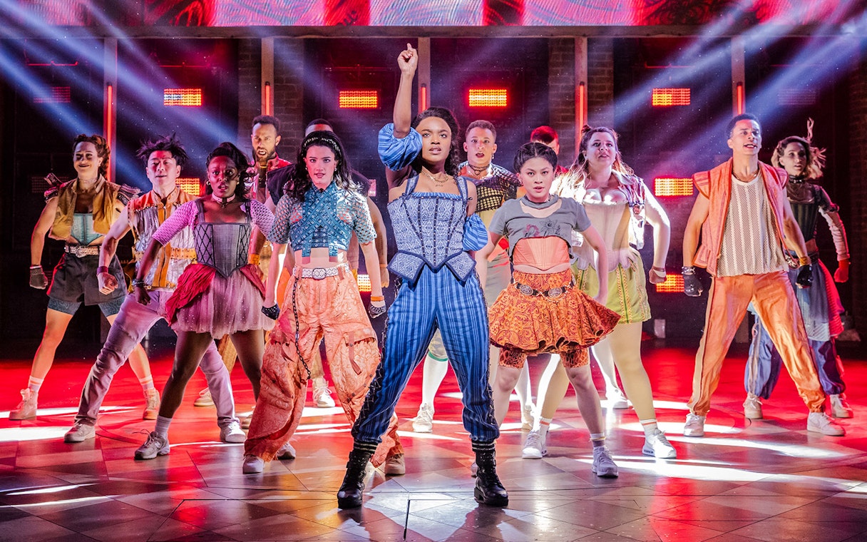 Performers on stage during "& Juliet" musical with vibrant costumes and dynamic lighting.