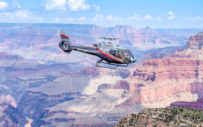 Helicopter flying over Grand Canyon South Rim during scenic tour.