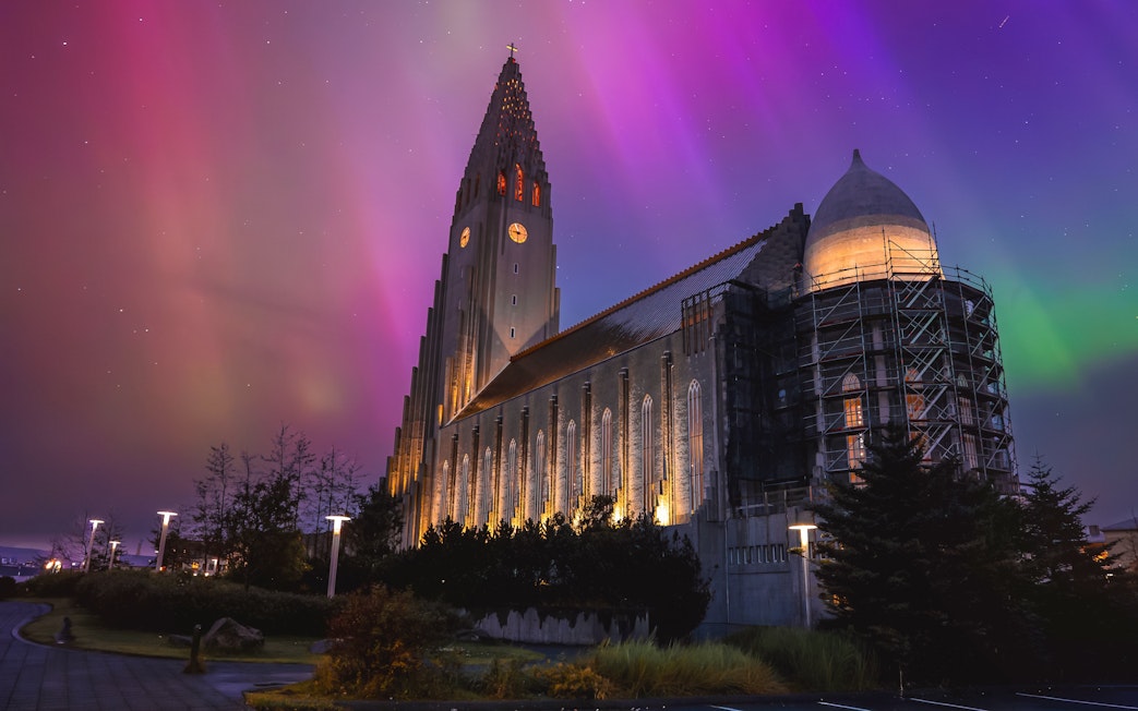 Illuminated church tower under green aurora in Reykjavik, Iceland.