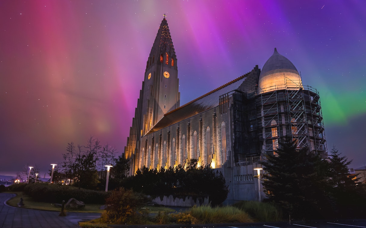 Illuminated church tower under green aurora in Reykjavik, Iceland.