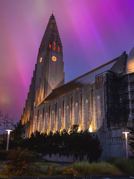 Illuminated church tower under green aurora in Reykjavik, Iceland.